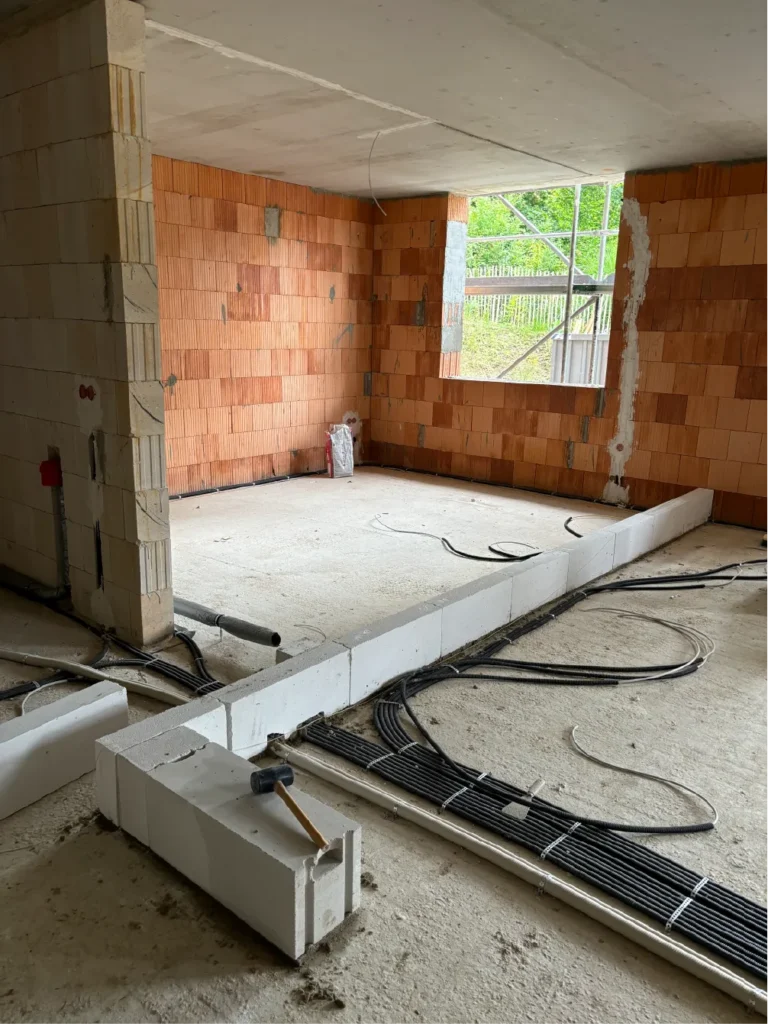 Rohbau eines Wohnraums mit verlegten Leitungen und Mauerwerk bei der Baukontrolle