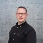 Bausachverständiger im Porträt vor Betonwand – professioneller Ansprechpartner für Bauschäden und Gutachten